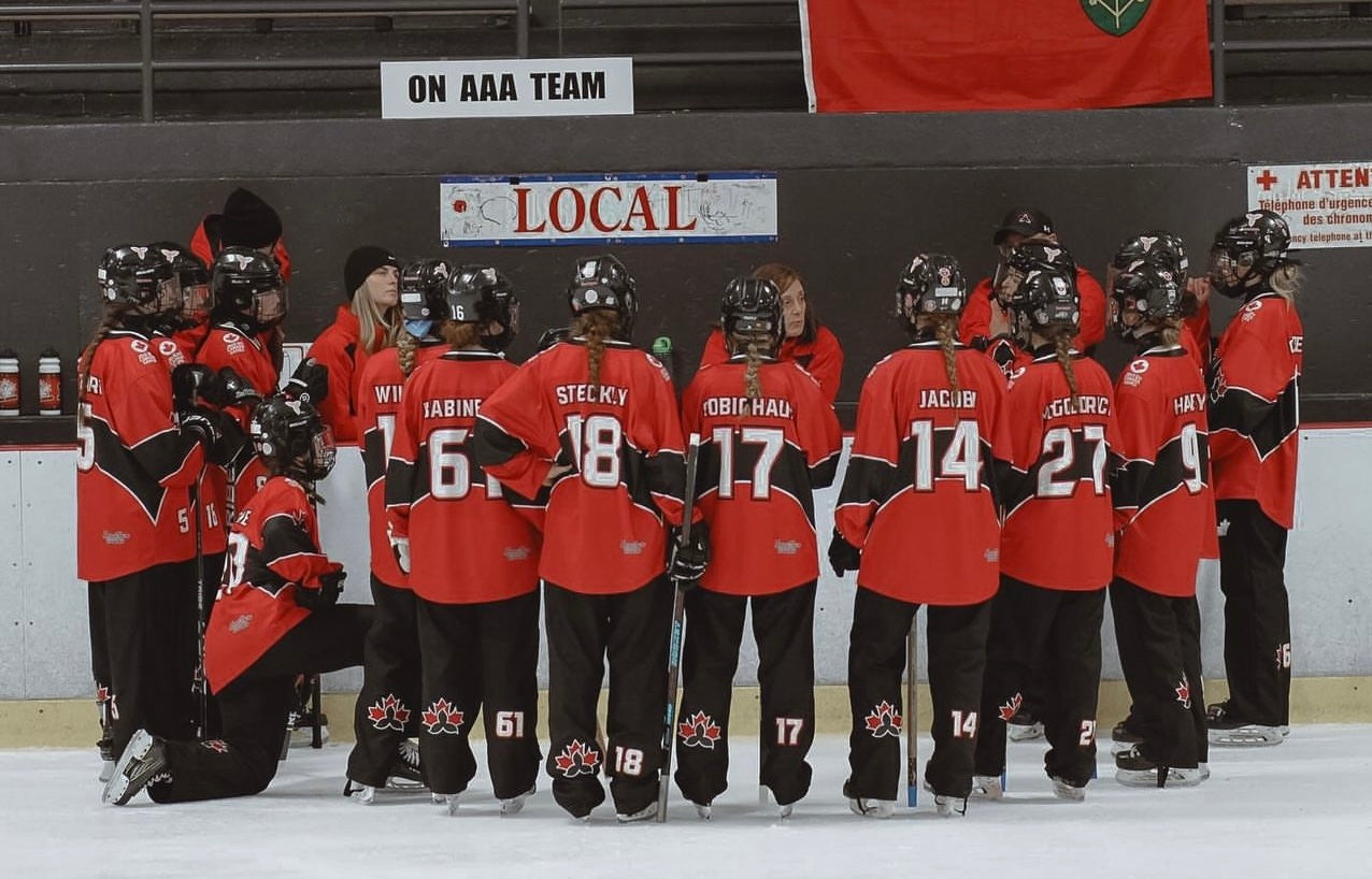 Ringette team wearing matching ringette jerseys in red team colours] — designed in Canada by Hometown Rivalry